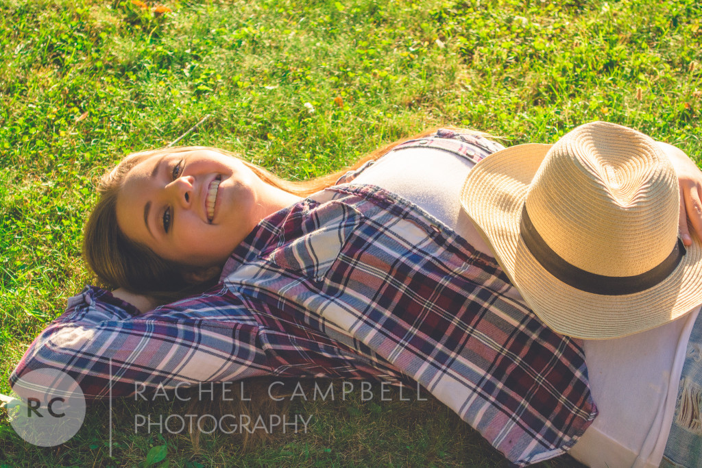 Senior portrait of a young woman laying in the grass holding a cowboy hat in Solon Ohio