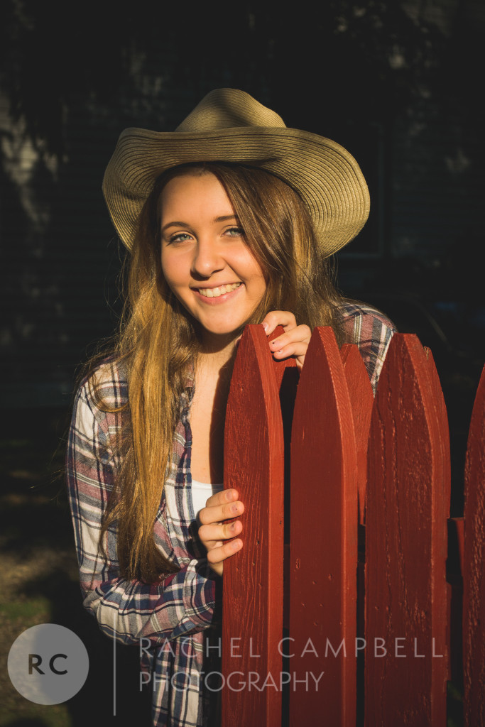 Senior portrait of a young woman leaning on a fence wearing a cowboy hat in Solon Ohio