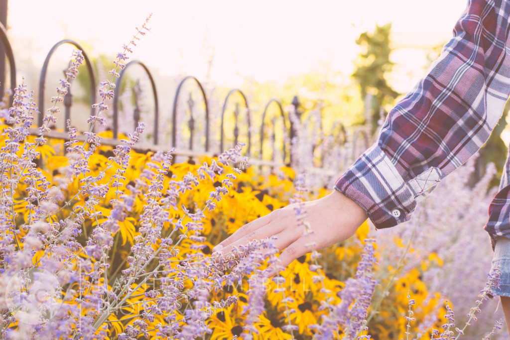 Senior portrait of a young woman walking along a gate with flowers in Solon Ohio