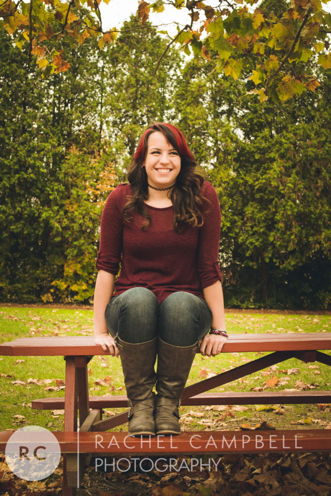 Senior portrait of a young woman sitting on a picnic table in a park in Solon Ohio