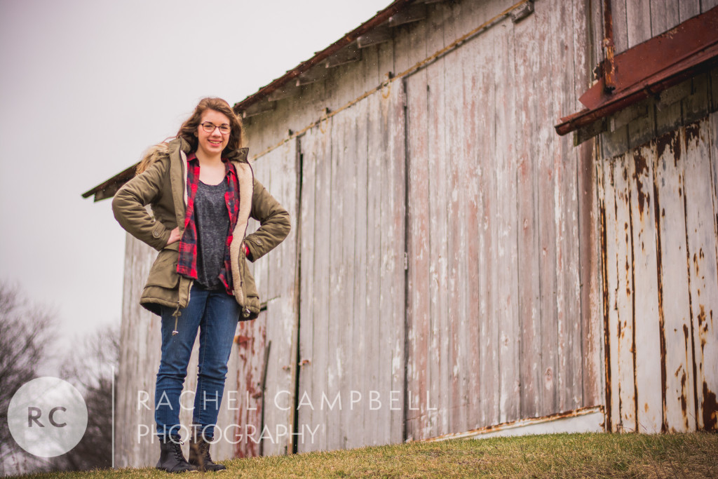 Senior portrait of a young woman standing near a barn wearing a winter coat in Solon Ohio