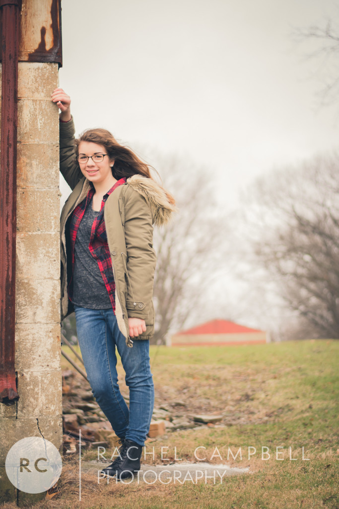 Senior portrait of a young woman leaning against a stone wall in a winter coat in Solon Ohio
