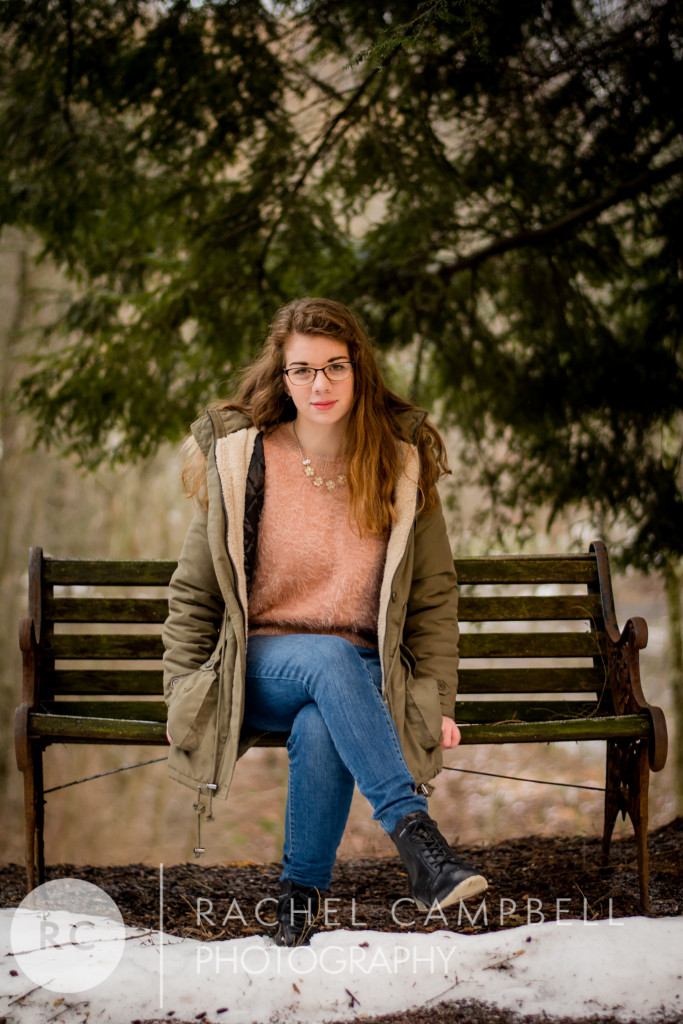 Senior portrait of a young woman sitting on a bench in her winter coat during winter in Solon Ohio