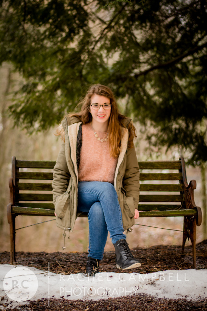 Senior portrait of a young woman sitting on a bench in her winter coat in winter in Solon Ohio