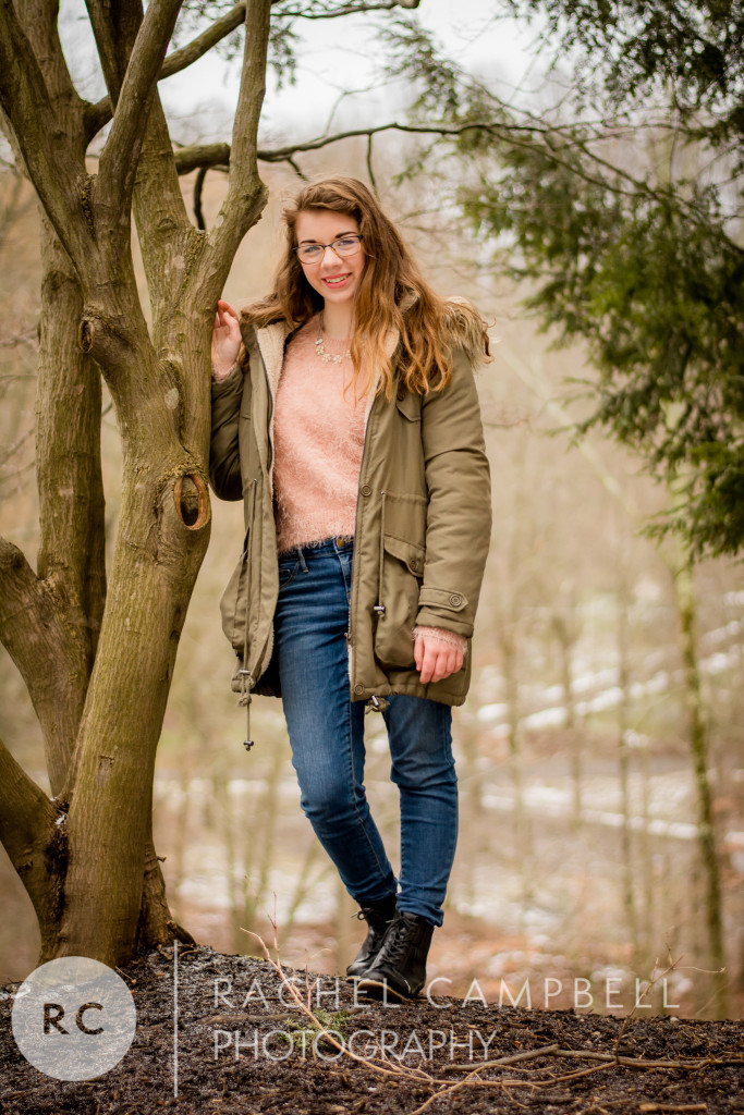 Senior portrait of a young woman leaning against a tree with her winter coat on in Solon Ohio