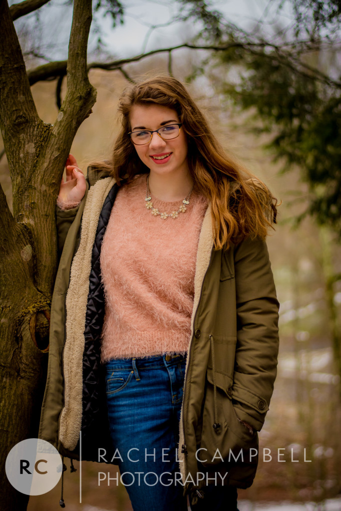 Senior portrait of a young woman leaning against a tree with her winter coat on in Solon Ohio
