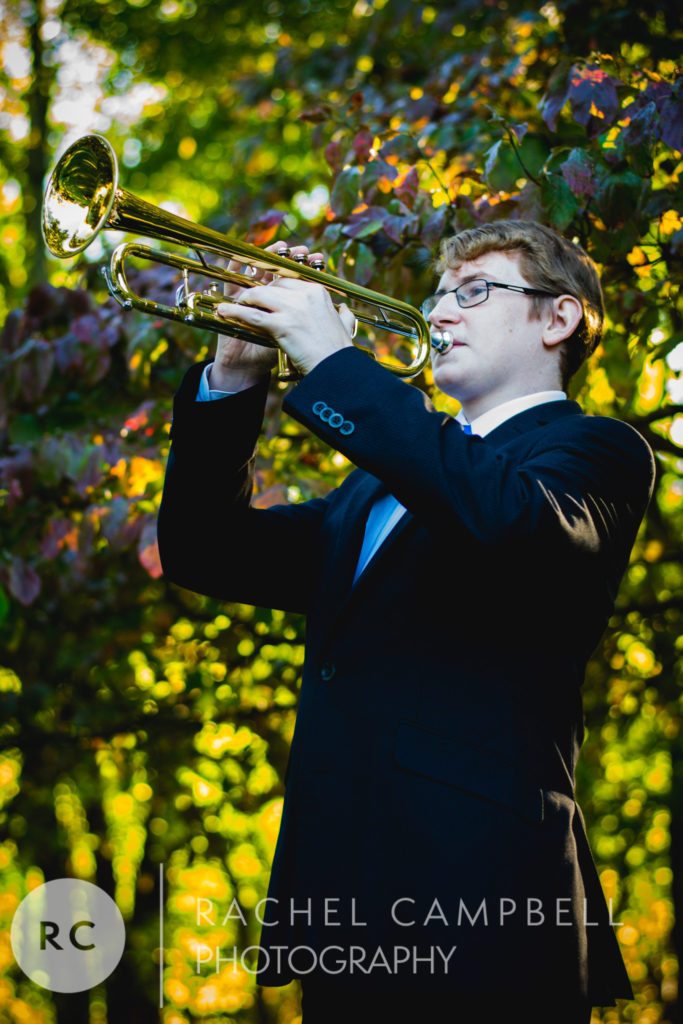 Senior picture of a young man playing his trumpet in front of trees in Solon Ohio