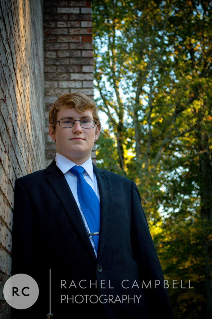 Senior portrait of a young man leaning against a brick wall in Solon Ohio