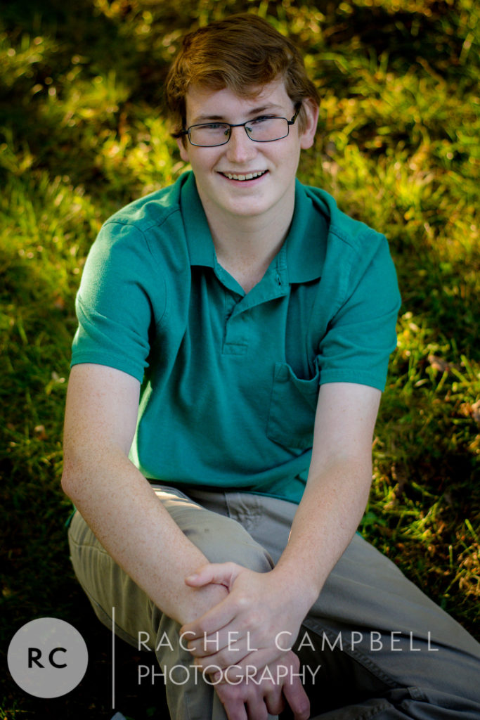 Senior portrait of a young man sitting in a patch of grass in Solon Ohio