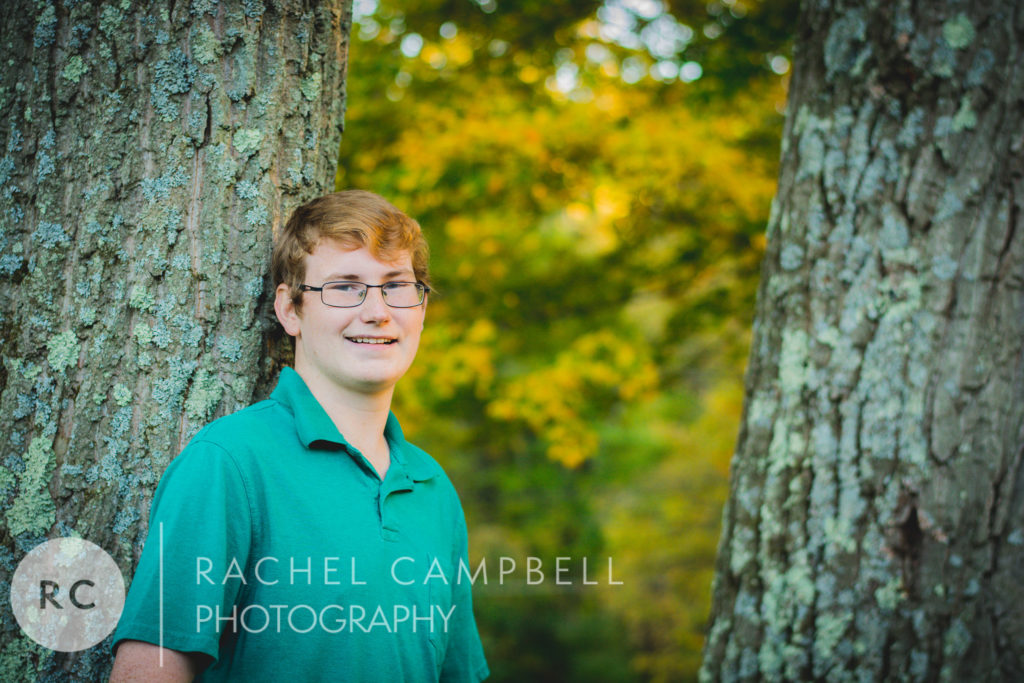 Senior portrait of a young man leaning against a tree in Solon Ohio