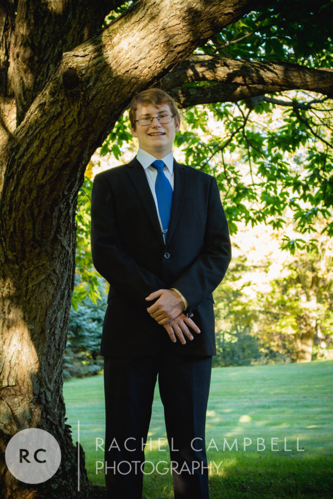 Senior portrait of a young man standing under a tree in Solon Ohio