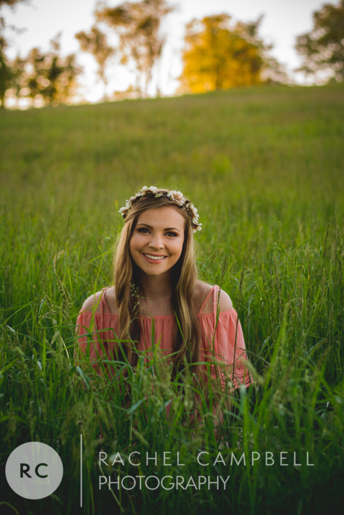 Senior portrait of a young woman sitting in a field at sunset in Solon Ohio