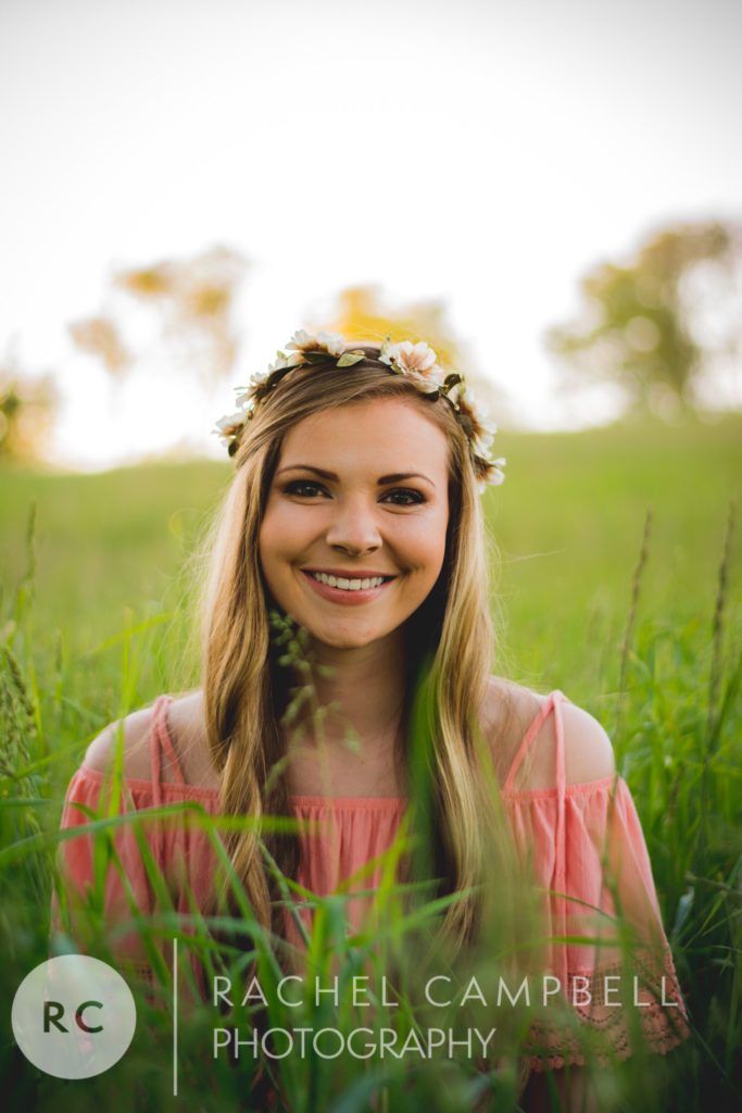 Senior photo of a young woman sitting in a field at sunset in Solon Ohio