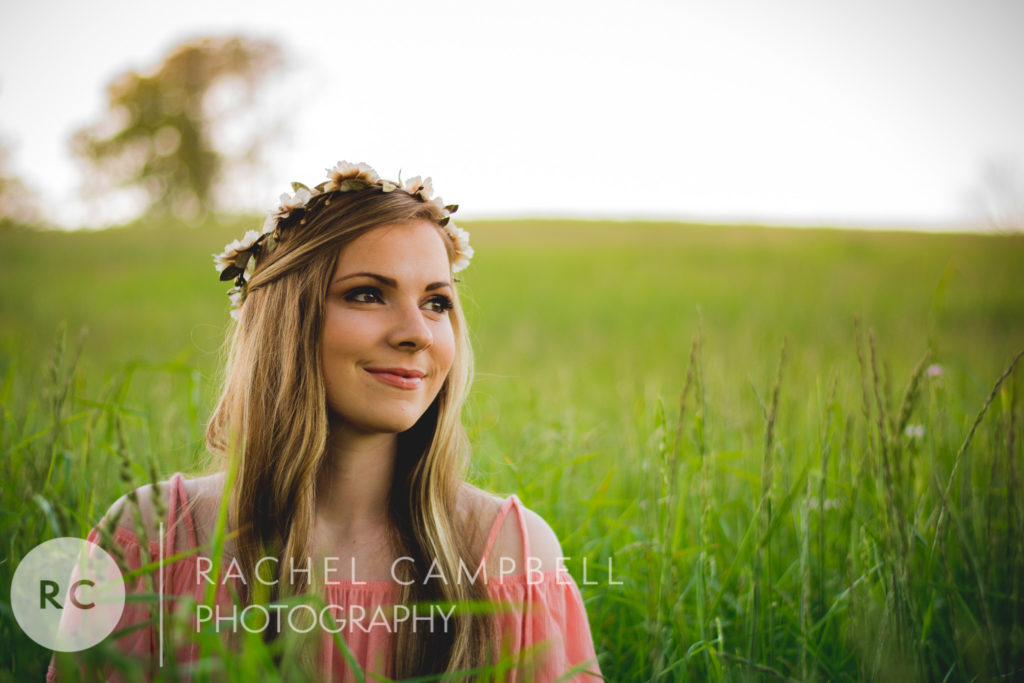 Senior portrait of a young woman sitting in a field at sunset in Solon Ohio