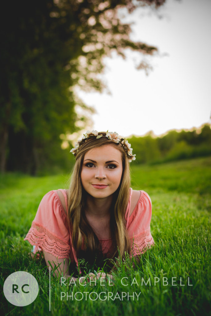 Senior photo of a young woman laying in grass at sunset in Solon Ohio