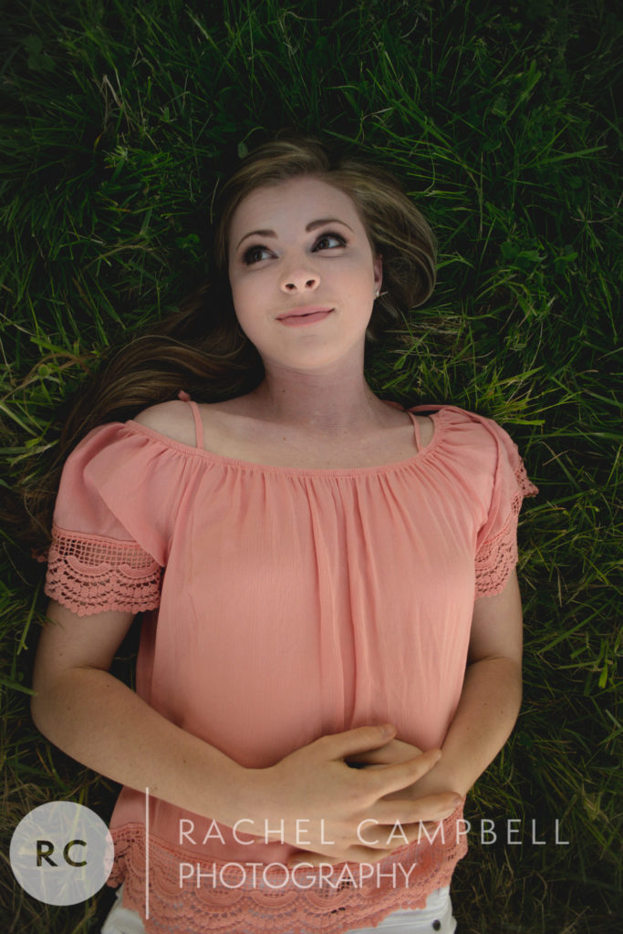 Senior portrait of a young woman laying in grass in Solon Ohio