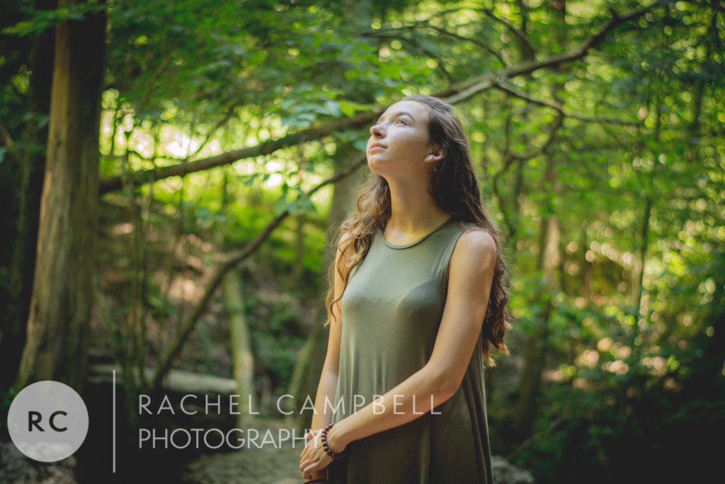 Senior photo of a young woman looking up at the trees in the woods in Solon Ohio
