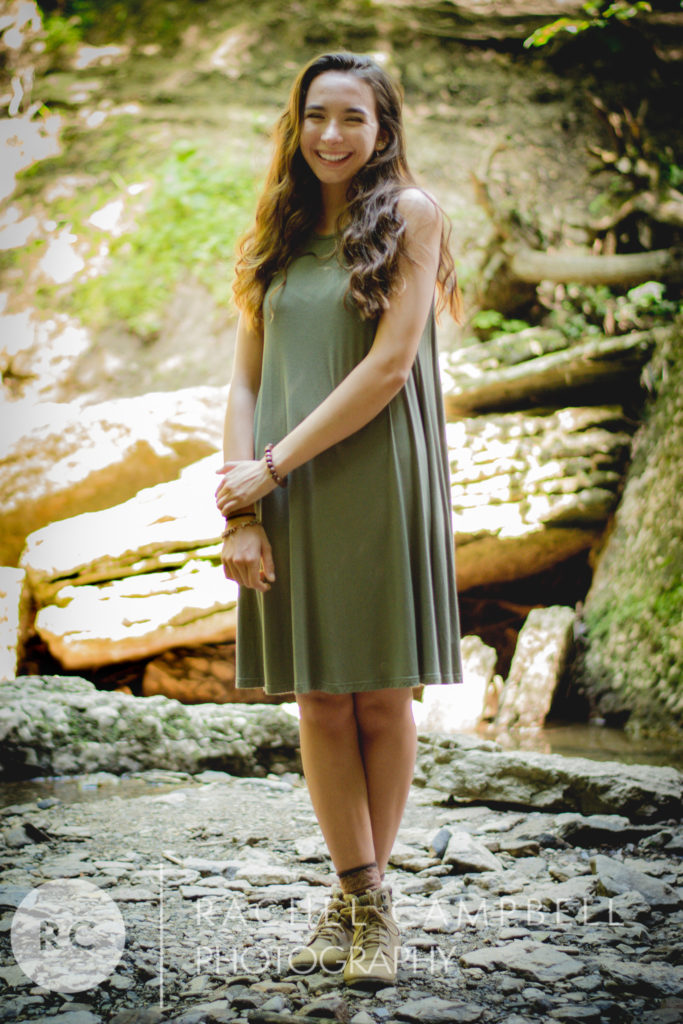 Senior portrait of a young woman standing on a rock in the woods in Solon Ohio