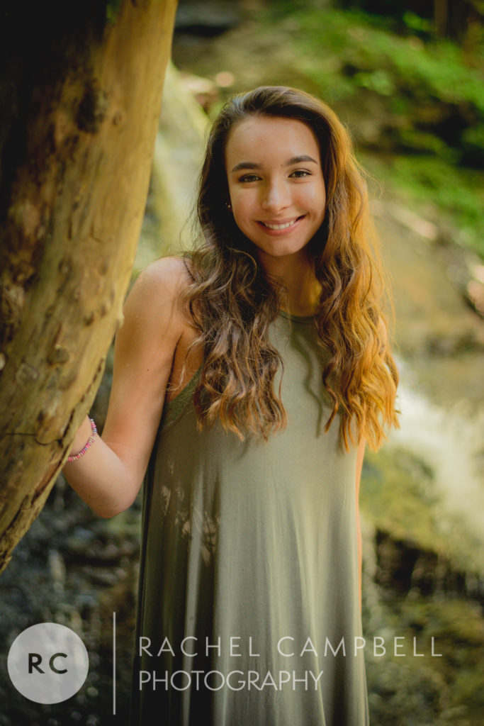 Senior photo of a young woman leaning on a tree in the woods in Solon Ohio