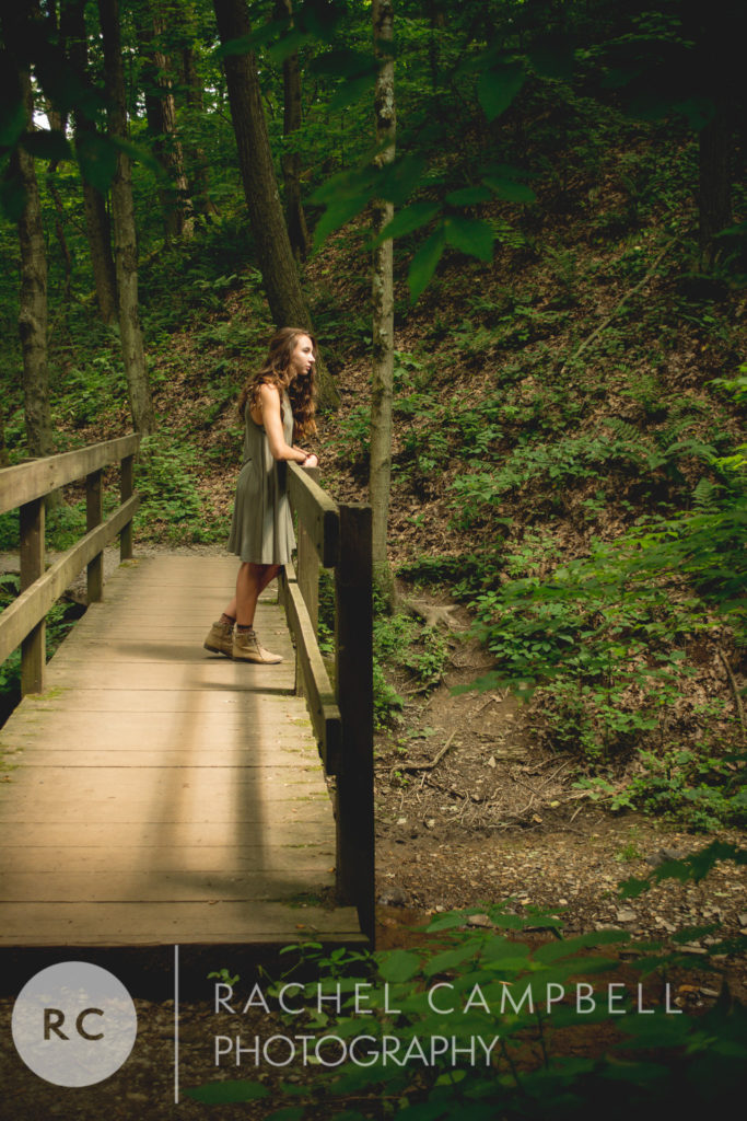 Senior portrait of a young woman looking over a bridge in the woods in Solon Ohio