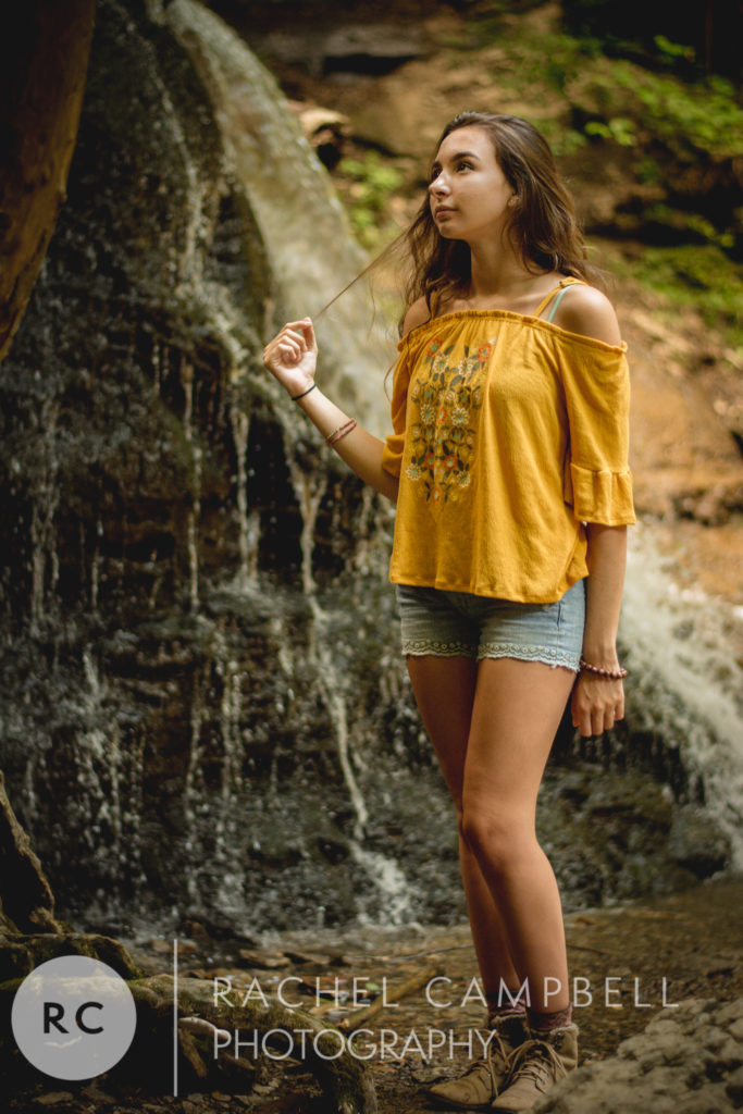 Senior portrait of a young woman standing near a waterfall in Solon Ohio