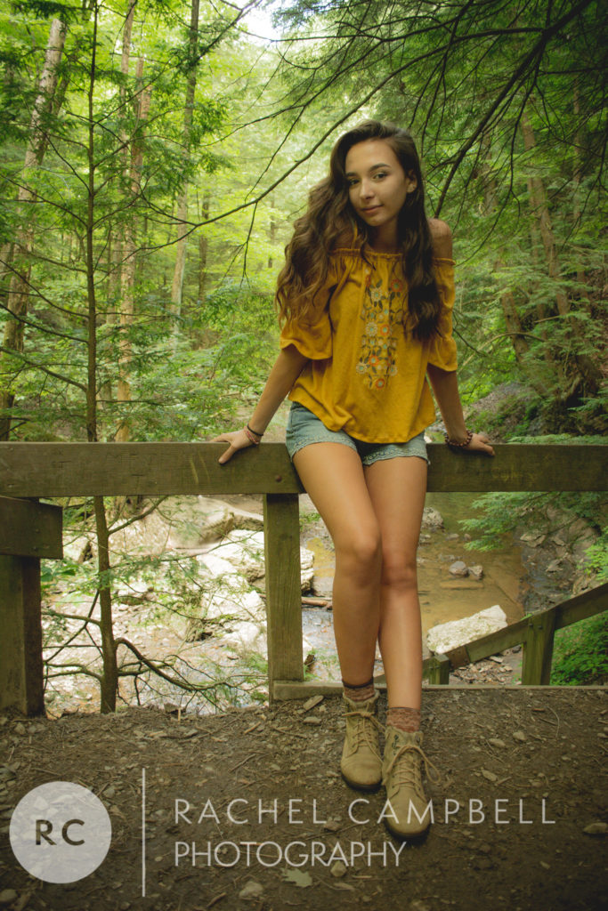 Senior portrait of a woman leaning on a railing in the woods in Solon Ohio