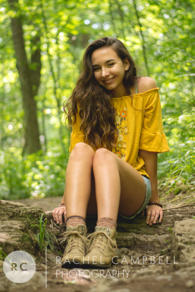 Senior portrait of a young woman sitting on a rock in the woods in Solon Ohio