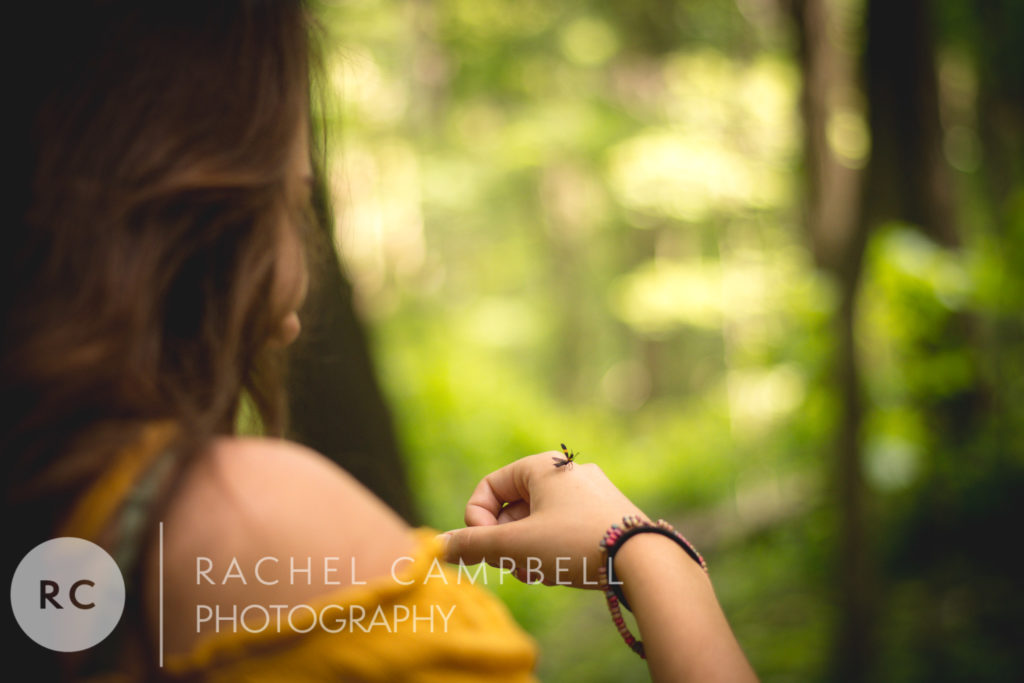 Senior portrait of a woman looking at a bug that landed on her hand in Solon Ohio