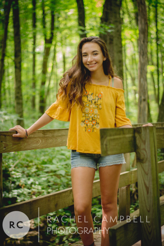 Senior portrait of a woman standing on a bridge in the woods in Solon Ohio
