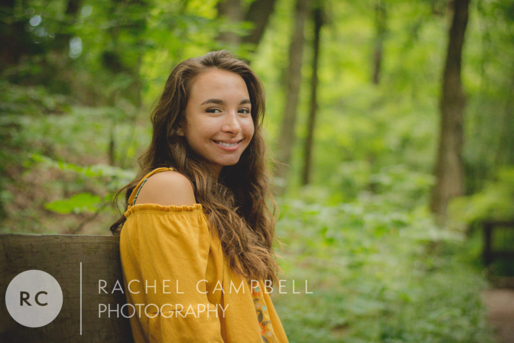 Senior portrait of a young woman sitting on a bench in the woods in Solon Ohio.