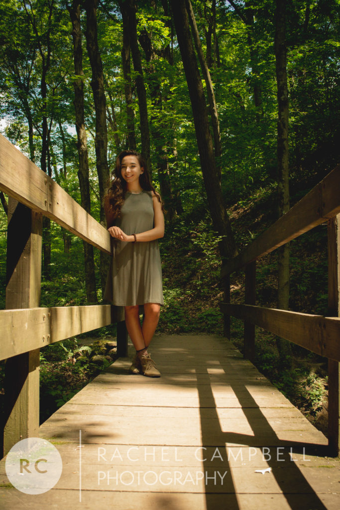 Senior portrait of a young woman standing on a bridge in the woods in Solon Ohio