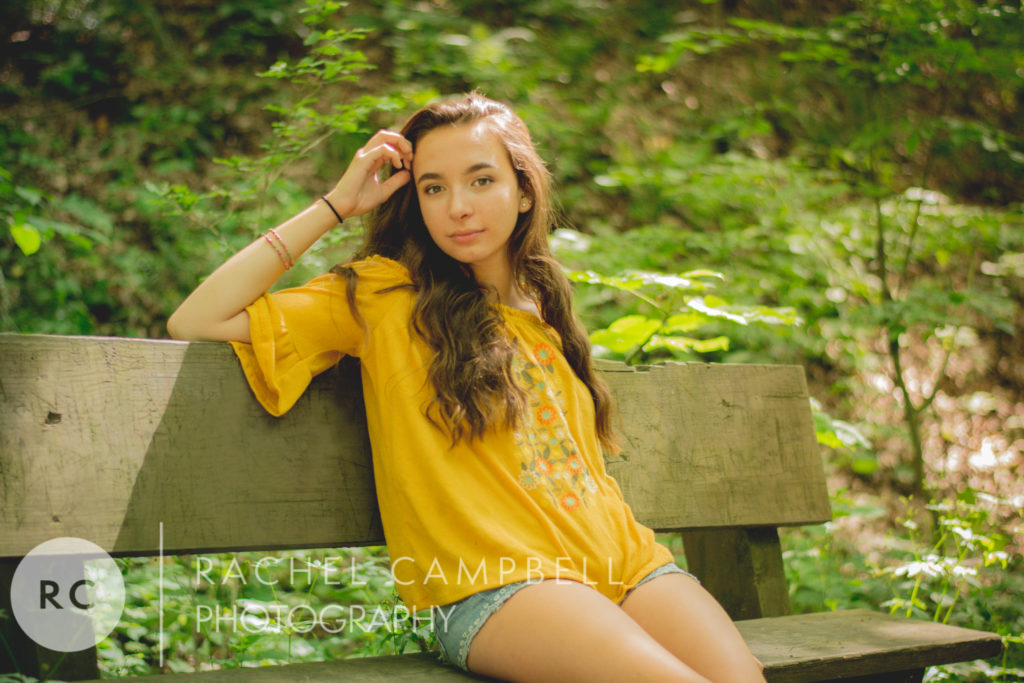 Senior portrait of a young woman sitting on a bench in the woods Solon Ohio