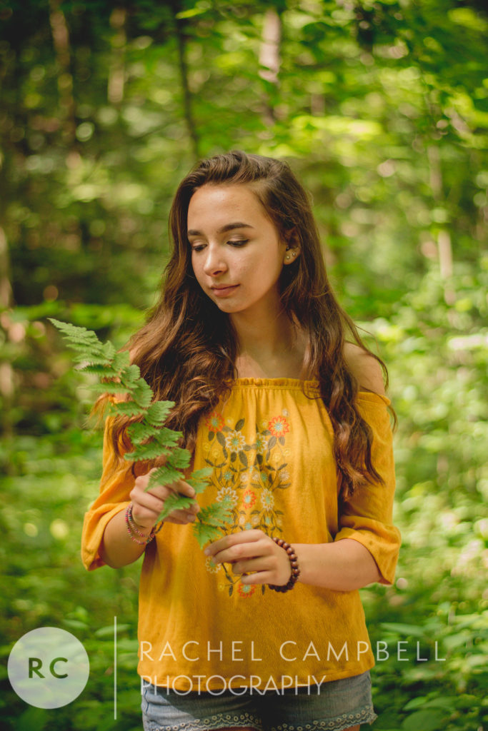 Senior portrait of a young lady holding a fern in the woods in Solon Ohio.