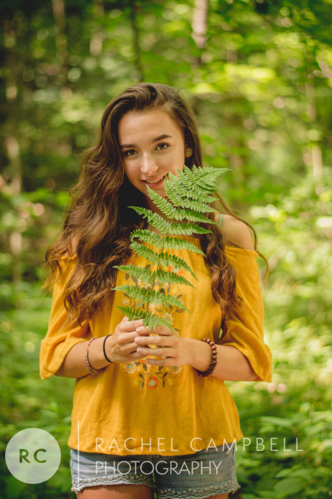 Senior portrait of a young woman holding a fern in the woods in Solon Ohio