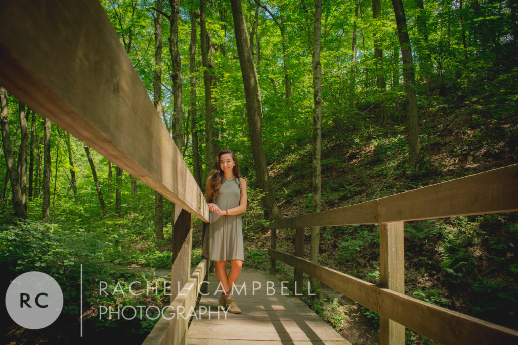 Senior portrait of a young lady standing on a bridge in the woods in Solon Ohio