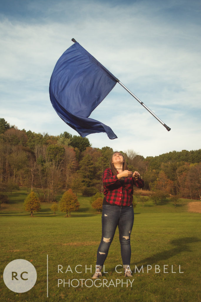 Senior photo of a young woman throwing a flag during a color guard routine in Solon Ohio