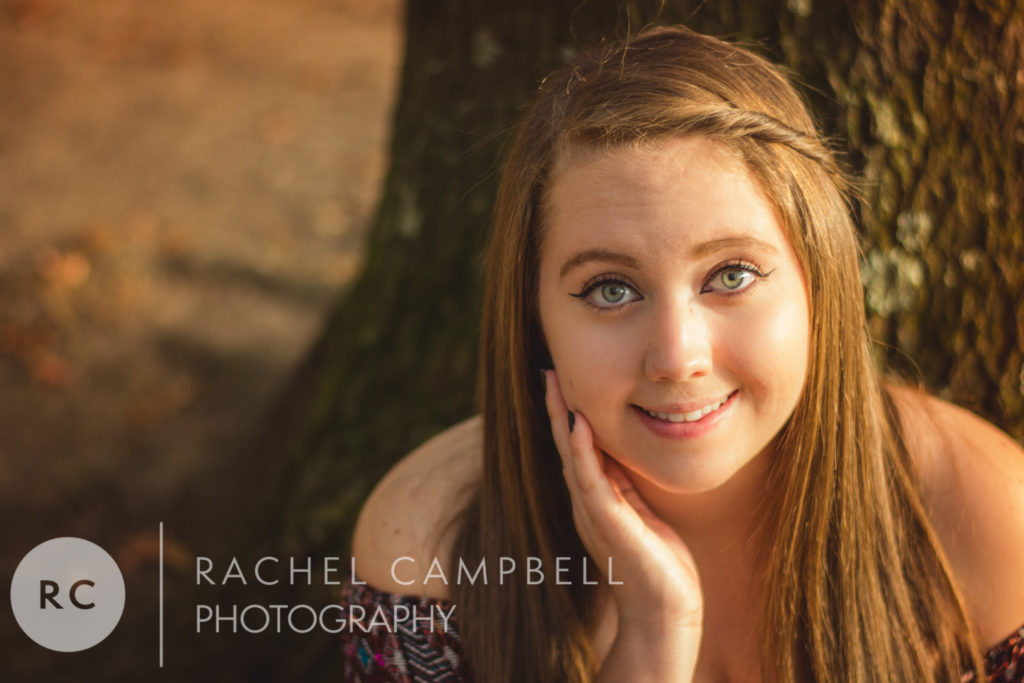 Senior portrait showing a young woman leaning against a tree at sunset in Solon Ohio