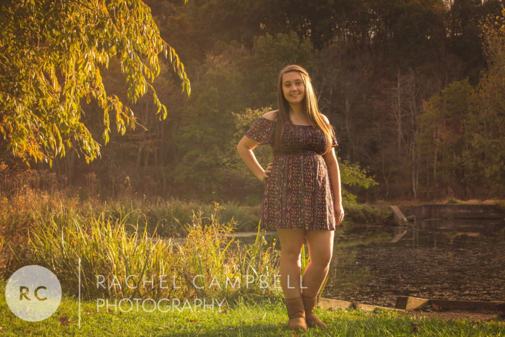 Senior portrait showing a young woman in front of a pond at sunset near Solon Ohio