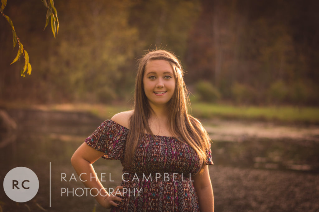 Senior portrait showing a young woman in front of a pond at sunset in Solon Ohio