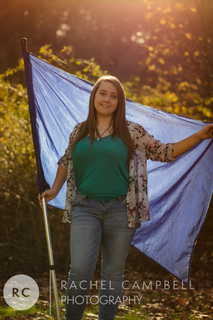 Senior portrait of a young woman holding a color guard flag at sunset in Solon Ohio