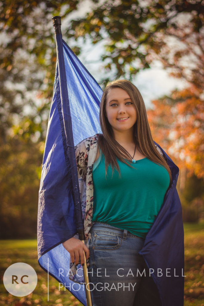 Senior portrait of a young woman wrapped in a color guard flag at sunset in Solon Ohio