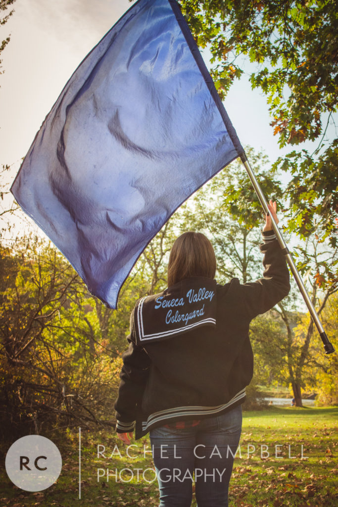 Senior portrait showing a young woman holding a flag in a varsity jacket in Solon Ohio